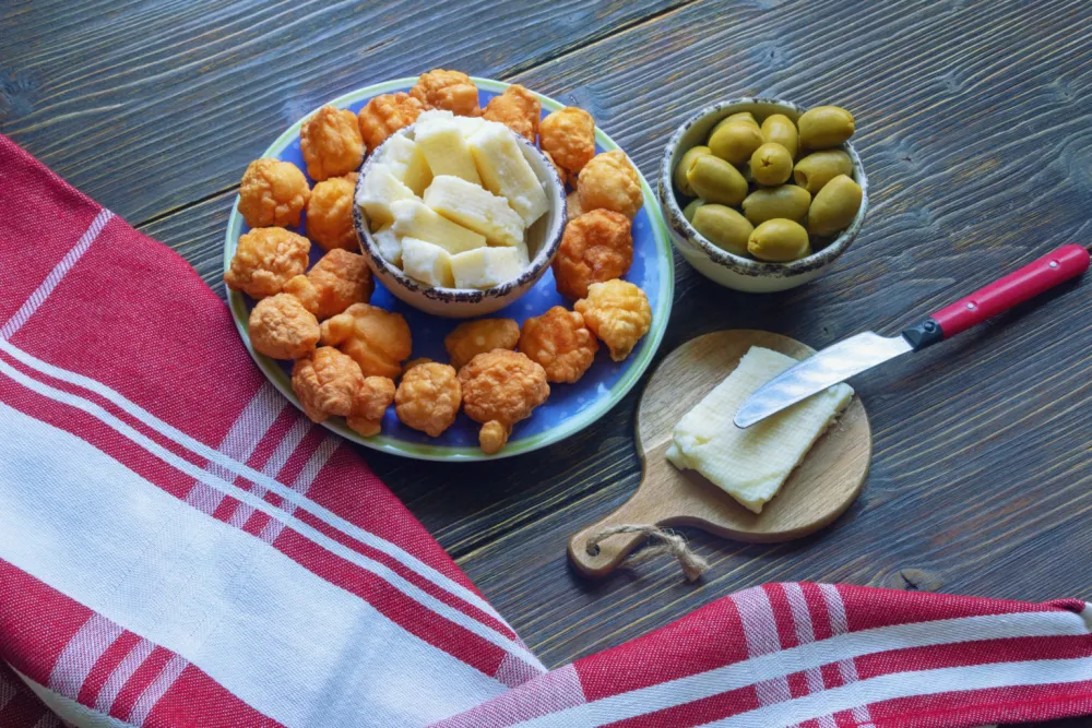 Balkan cuisine. Priganice (small fried cakes, donuts) with local cheese and olives on dark rustic table. Copy space