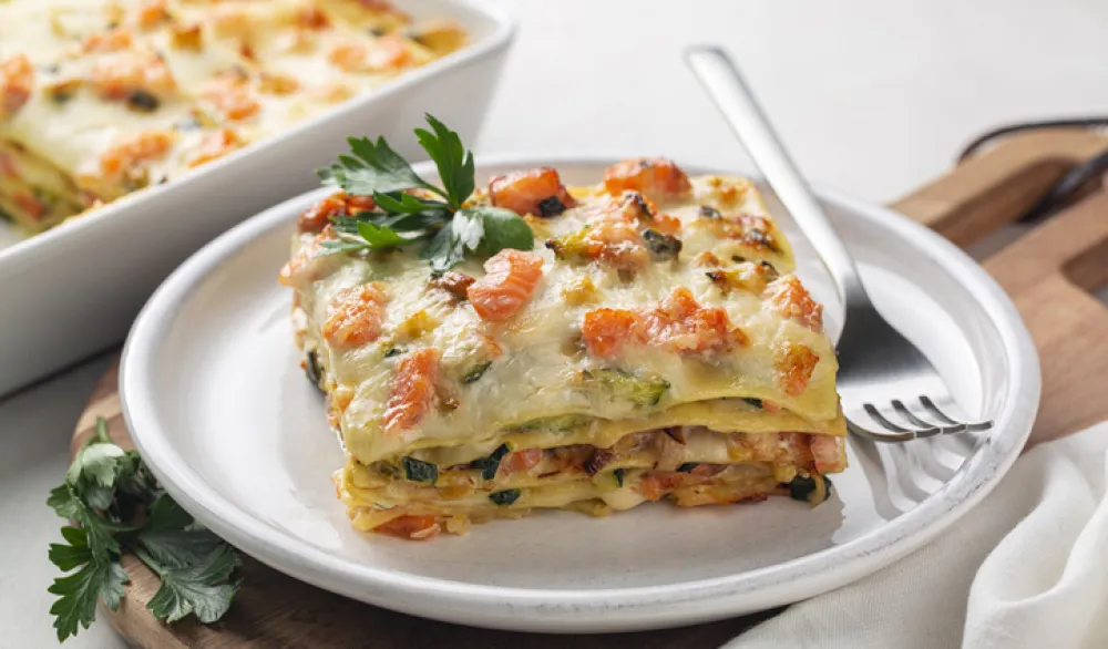Close up of Lasagna with salmon fish, zucchini, bechamel sauce, parmesan cheese and leek. Baked in oven italian pasta made of flat sheets.