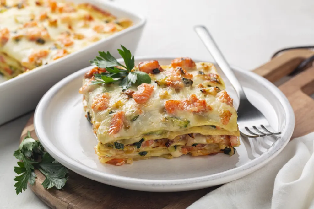 Close up of Lasagna with salmon fish, zucchini, bechamel sauce, parmesan cheese and leek. Baked in oven italian pasta made of flat sheets.