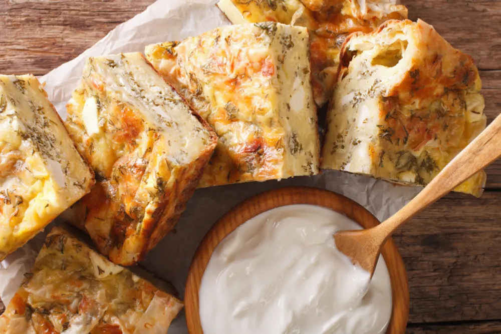 Serbian pie Gibanica with cheese, eggs and greens close-up on the table. Horizontal view from above<br>
