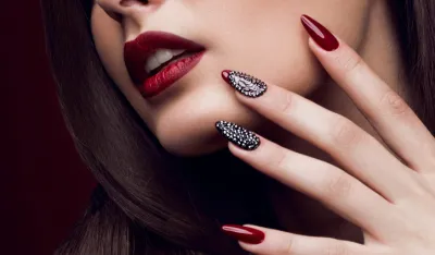 Pretty girl with unusual hairstyle, bright makeup, red lips and manicure design. Beauty face. Art nails. Studio portrait