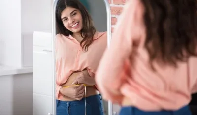 Reflection Of A Happy Woman Measuring Waist With A Tape