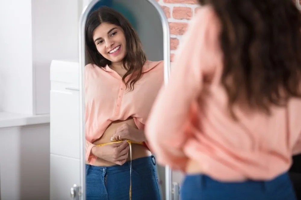 Reflection Of A Happy Woman Measuring Waist With A Tape