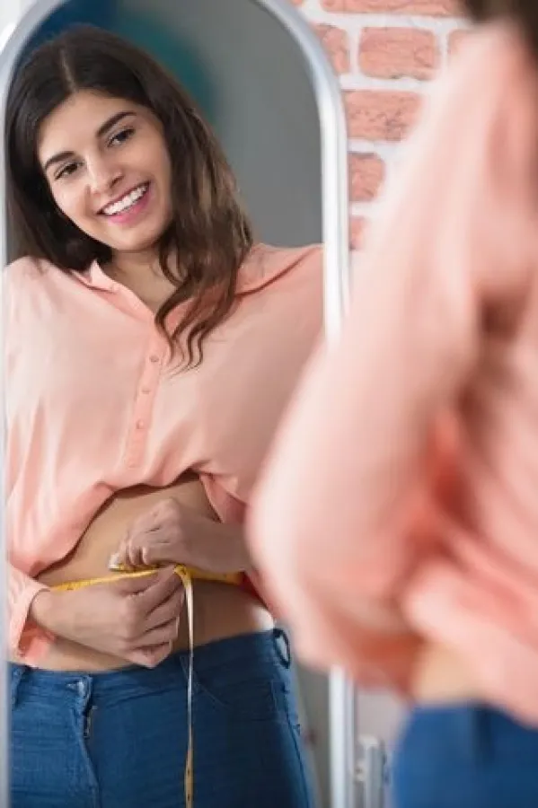Reflection Of A Happy Woman Measuring Waist With A Tape