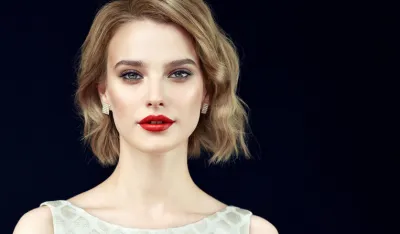 Portrait of beautifully looking young light blonde haired woman, dressed in a delicate evening makeup.Perfect model straightly gazing by kind, tender look at viewer. Beauty, elegance, hairstyling and cosmetic.