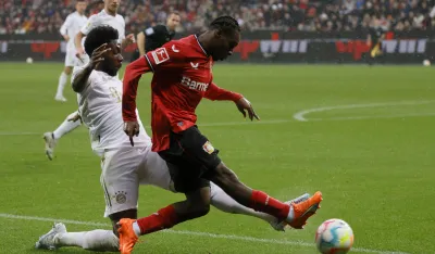 epa10532308 Leverkusen's Jeremie Frimpong (R) in action against Munich's Alphonso Davies (L) during the German Bundesliga soccer match between Bayer 04 Leverkusen and FC Bayern Munich in Leverkusen, Germany, 19 March 2023. EPA-EFE/RONALD WITTEK CONDITIONS - ATTENTION: The DFL regulations prohibit any use of photographs as image sequences and/or quasi-video.