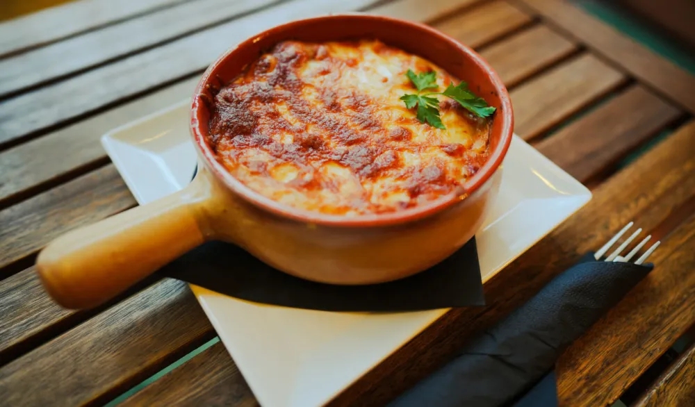Close up shot of a freshly baked lasagna in a round pot.