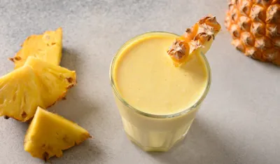 Traditional Pineapple lassie or smoothie on gray background. Traditional Asian beverage of pineapple, yogurt and ice. View from above. Copy space.