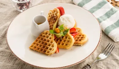 Fresh heart shaped waffles with ice cream and syrup served on the table studio shot