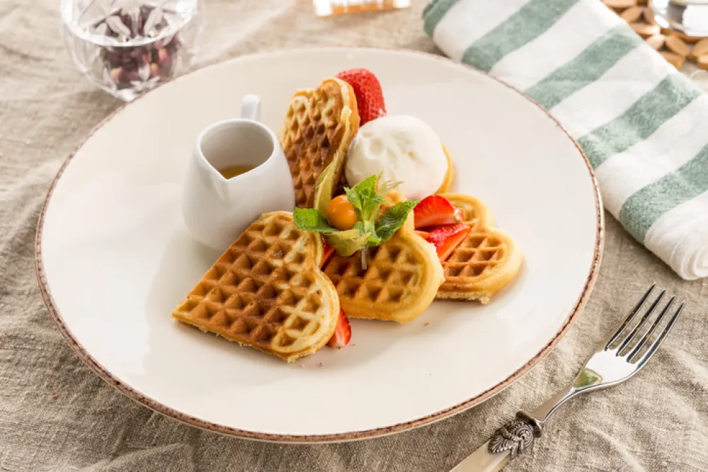 Fresh heart shaped waffles with ice cream and syrup served on the table studio shot