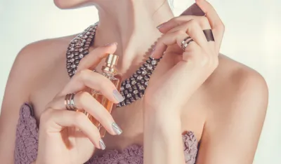 Woman on white background applying perfume on her wrist