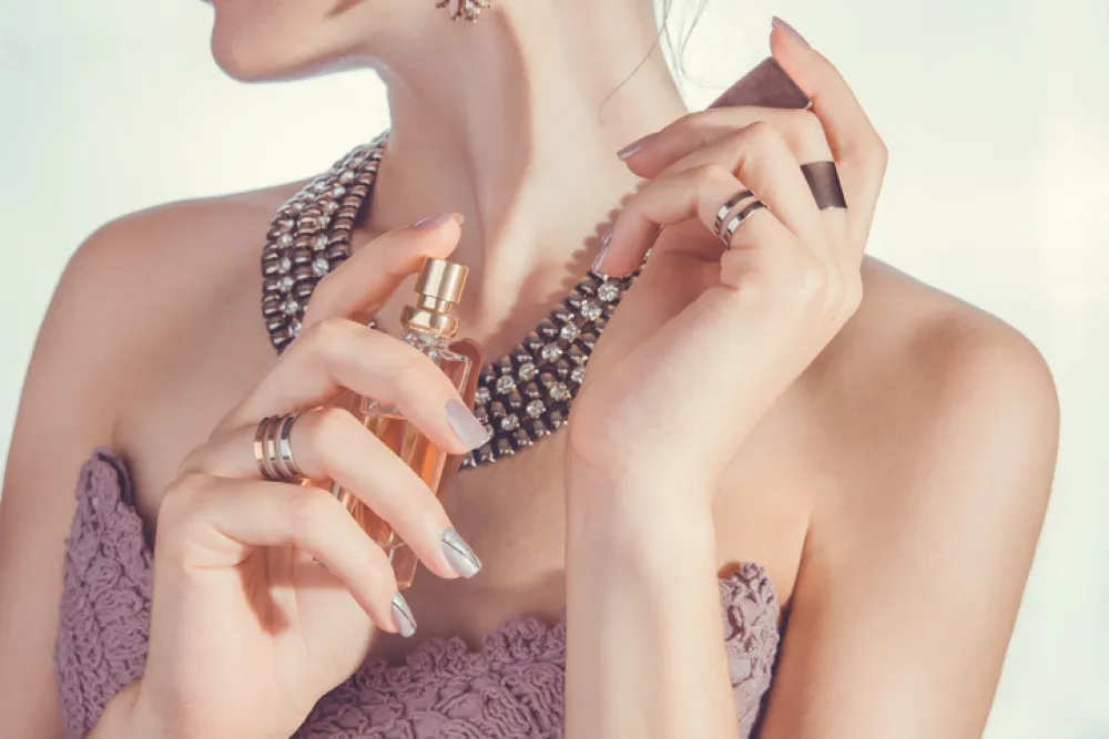 Woman on white background applying perfume on her wrist