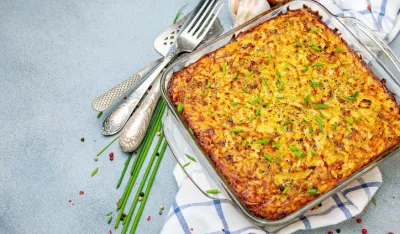 Traditional jewish dish potato kugel with green onions on a textured gray background. Top view.
