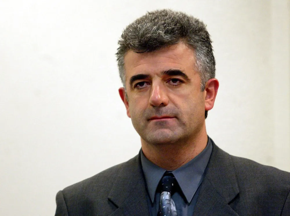 Dusko Jovanovic sits during his initial appearance before the War Crimes Tribunal in The Hague, December 5, 2003. Jovanovic, editor in chief of the paper DAN in Montenegro, has published the real name of the protected witness K32. He is being charged with contempt of the tribunal.  REUTERS/Pool