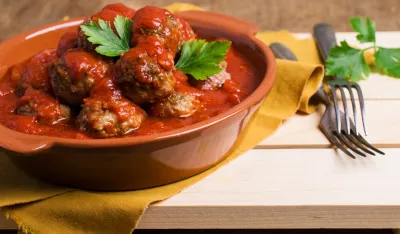 Traditional spicy meatballs in tomato sauce on wooden background. Selective focus.