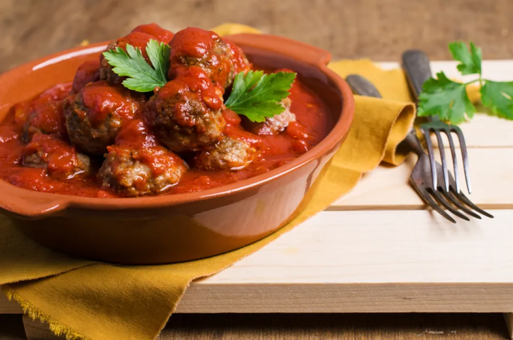 Traditional spicy meatballs in tomato sauce on wooden background. Selective focus.