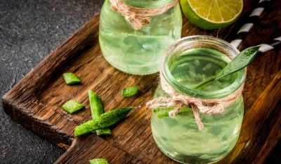Healthy exotic detox drink, aloe vera or cactus juice with lime, on dark background copy space