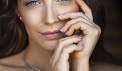 Close-up portrait of a 40 years old blue eyed woman. She touching her face and looking at camera. Sin care concept in the age after 40.