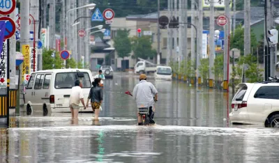 Residents wade through floodwaters in a streeet in Kukui, central Japan, on Monday July 19, 2004, a day after torrential rains from a storm caused a river flowing through this prefectual capital to break at several places. (AP Photo/Kyodo) ** JAPAN OUT NO SALES MANDATORY CREDIT **