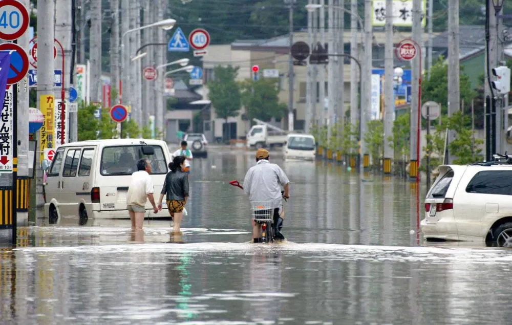 Residents wade through floodwaters in a streeet in Kukui, central Japan, on Monday July 19, 2004, a day after torrential rains from a storm caused a river flowing through this prefectual capital to break at several places. (AP Photo/Kyodo) ** JAPAN OUT NO SALES MANDATORY CREDIT **
