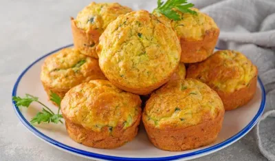 Homemade zucchini muffins with cheese, garlic and herbs on a plate on a gray concrete background. Vegetarian dish. Copy space