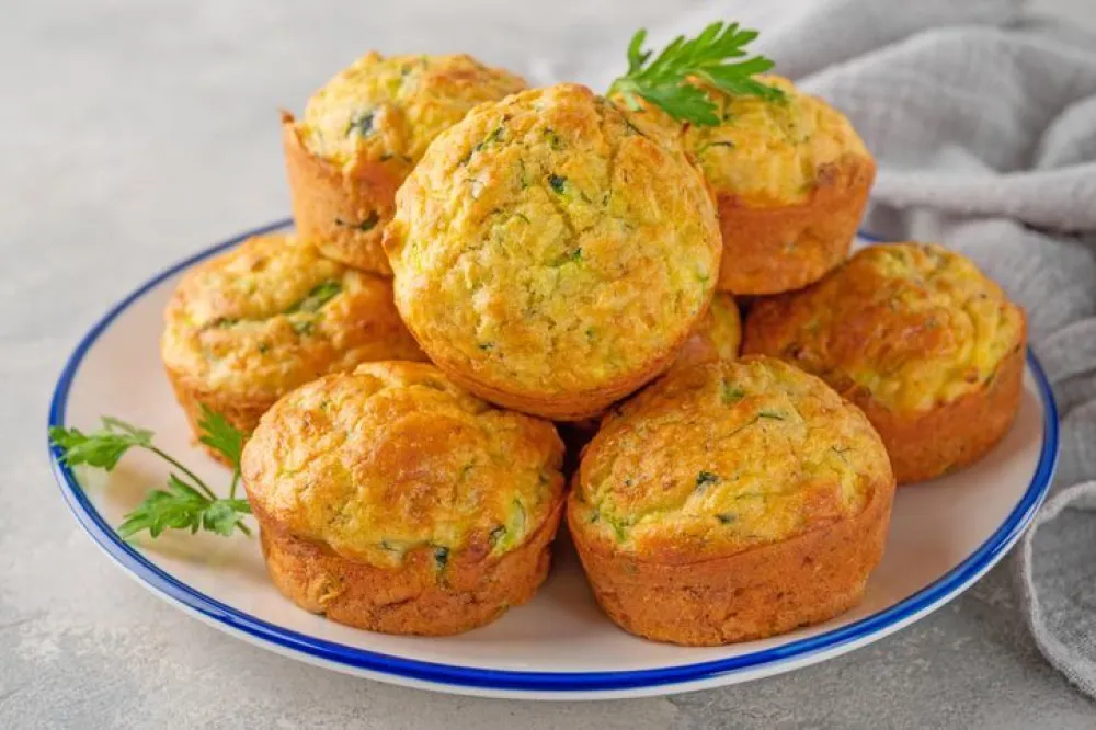 Homemade zucchini muffins with cheese, garlic and herbs on a plate on a gray concrete background. Vegetarian dish. Copy space