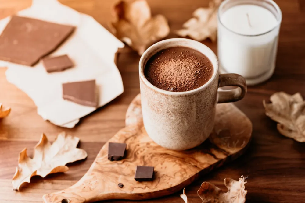 Close-up of hot chocolate in a ceramic mug on the table. Autumn or winter cozy still life.
