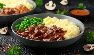 Slow Cooked Steak Diane Casserole with mushroom. mashed potatoes and green peas.