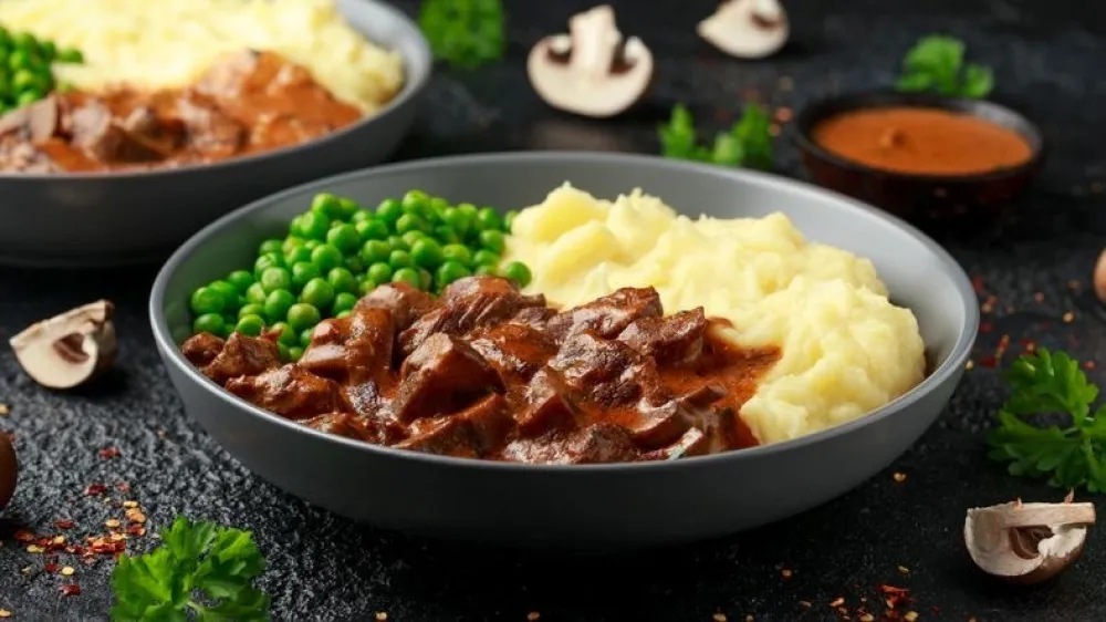 Slow Cooked Steak Diane Casserole with mushroom. mashed potatoes and green peas.