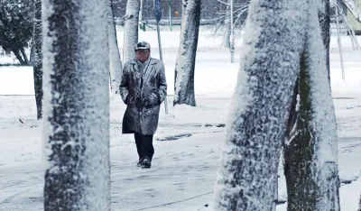 A man walks in a park during a short burst of snowfall in Warsaw, Poland, Sunday Nov. 21, 2004. The temperature in Warsaw was 0 degress Celsius. (AP Photo/Alik Keplicz)