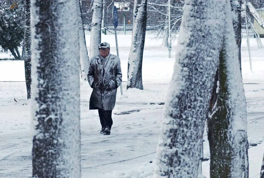 A man walks in a park during a short burst of snowfall in Warsaw, Poland, Sunday Nov. 21, 2004. The temperature in Warsaw was 0 degress Celsius. (AP Photo/Alik Keplicz)