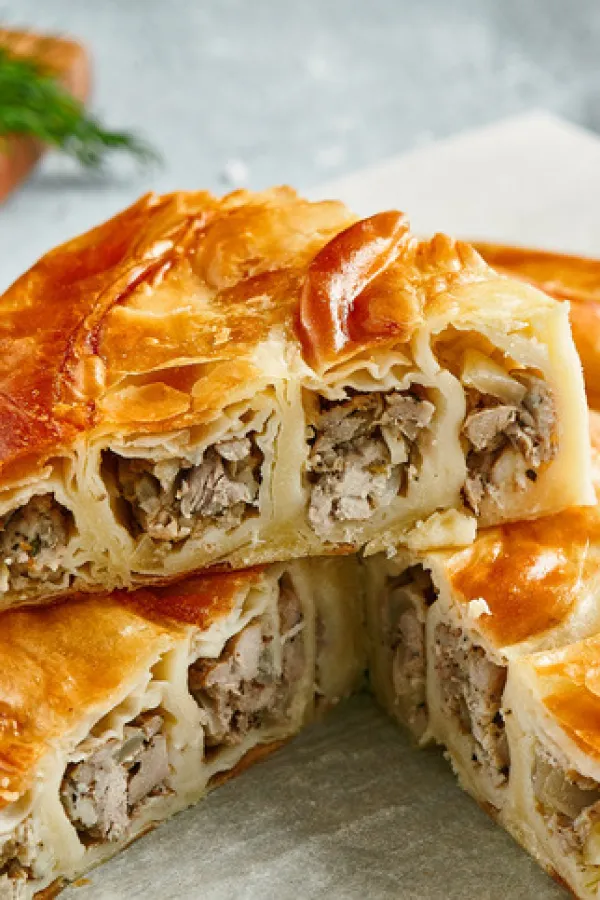 Classic turkish pie with meat on wooden board. Composition with burek pie on concrete background with textile and spices. Balkan pie with minced meat in rustic style on gray table