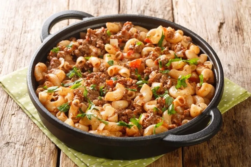 American Hamburger Goulash with Elbow Macaroni closeup in the pan on the wooden table. Horizontal<br>