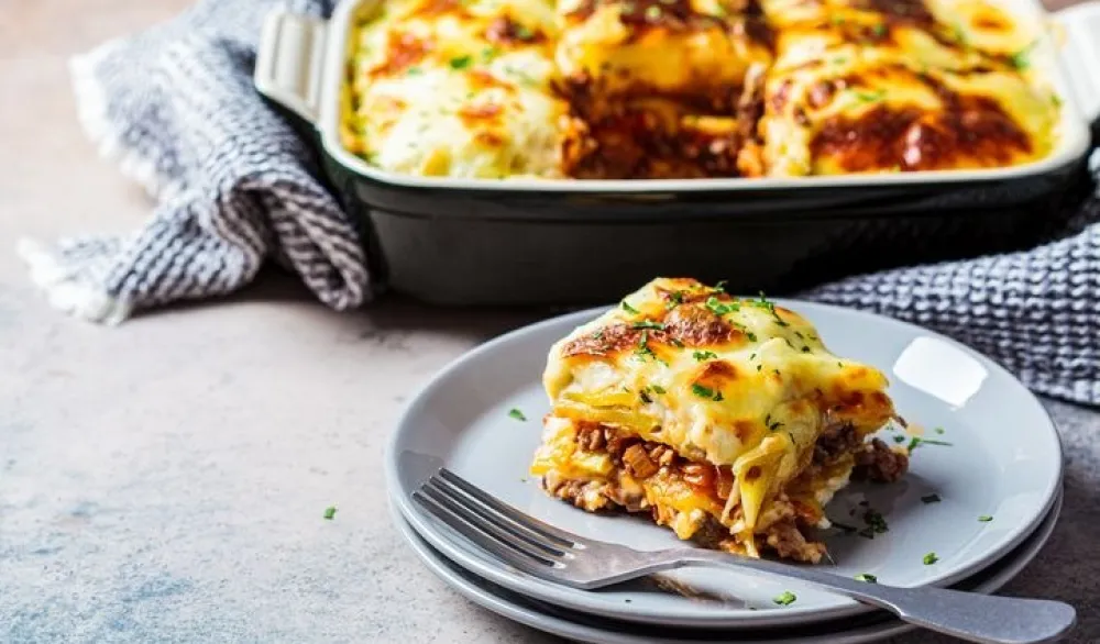 Traditional Greek potato and meat casserole with cheese - moussaka, dark background. Greek cuisine concept.