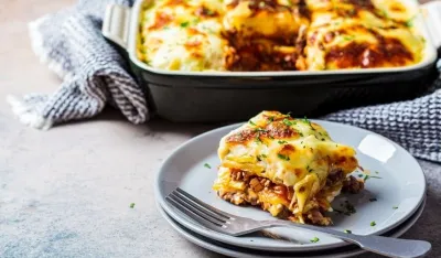 Traditional Greek potato and meat casserole with cheese - moussaka, dark background. Greek cuisine concept.
