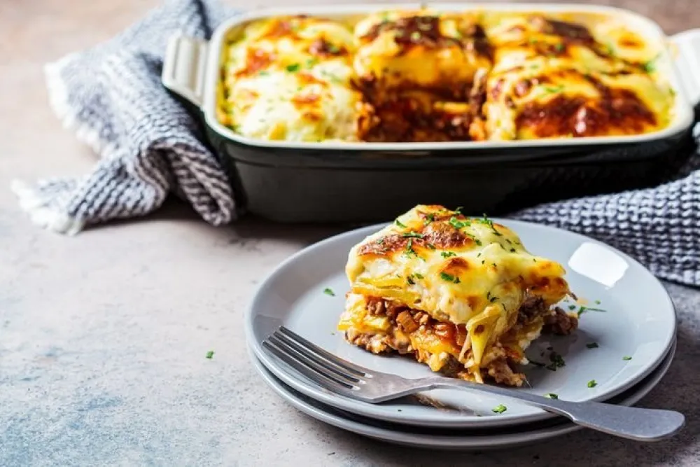 Traditional Greek potato and meat casserole with cheese - moussaka, dark background. Greek cuisine concept.