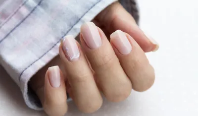 Beautiful groomed woman's hands with feminine nails on the light gray background. Manicure, pedicure beauty salon concept. Empty place for text or logo