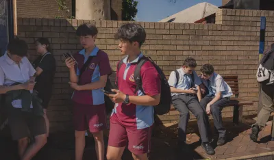 Đaci dok čekaju autobus provode vrijeme na telefonu