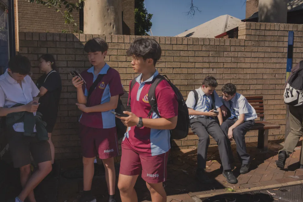 Đaci dok čekaju autobus provode vrijeme na telefonu