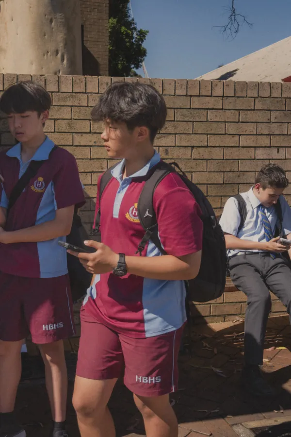 Đaci dok čekaju autobus provode vrijeme na telefonu