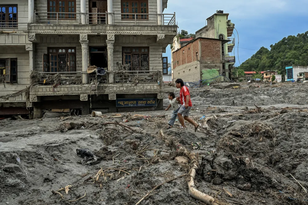 Ljudi hodaju po blatu i nanosu u oblasti Devighat u okrugu Nuakot u Nepalu u petak, 28. avgusta 2026. godine, nakon razorne bujične poplave.